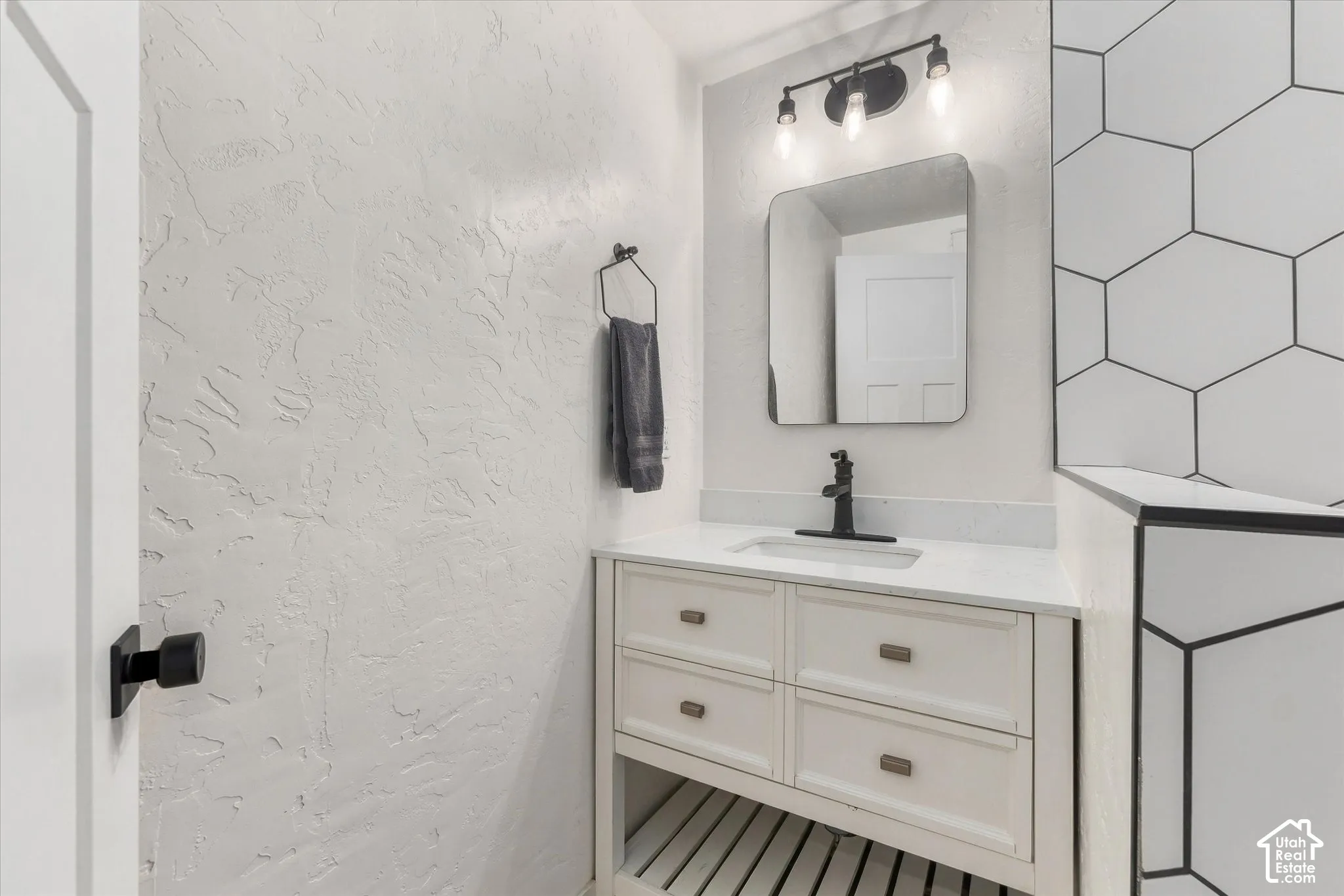 White vanity with built-in storage and open shelving, quartz countertop, and integrated sink