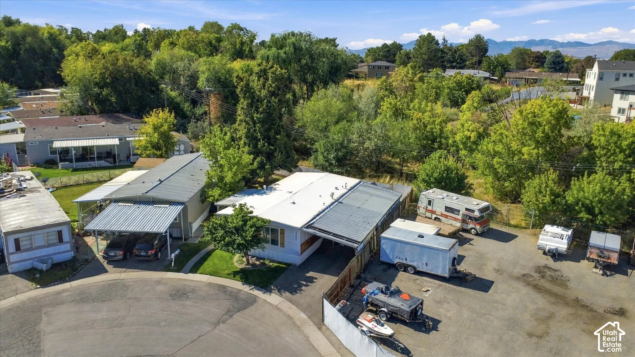 Property with two distinct rooflines, a carport, and an expansive gravel parking area