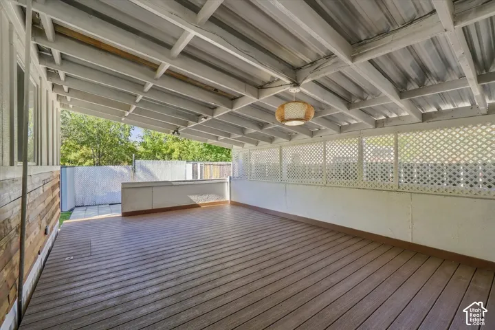Covered outdoor patio featuring wood-finish decking, white lattice detailing, and an integrated ceiling light fixture