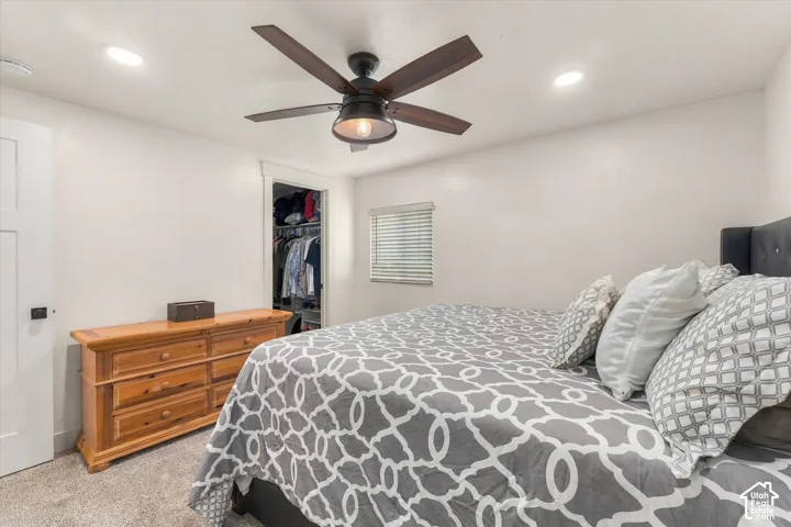 Recessed lighting, wood-finish ceiling fan, window with blinds, carpet flooring, and an open closet with shelving