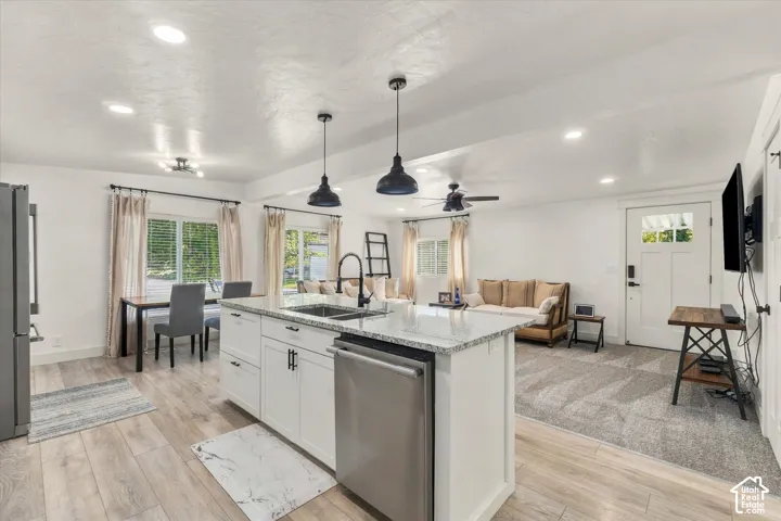 Open-concept layout featuring wood-finish flooring, recessed lighting, and a modern kitchen island with integrated sink