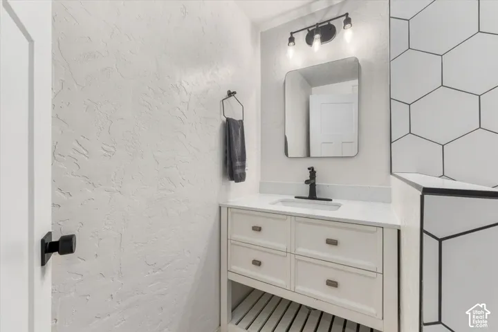 White vanity with built-in storage and open shelving, quartz countertop, and integrated sink