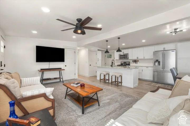 Open-concept living space featuring a ceiling fan, recessed lighting, and light wood-finish flooring