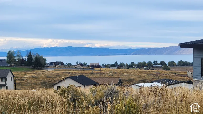Expansive landscape featuring a large body of water, distant mountains, and scattered residential structures