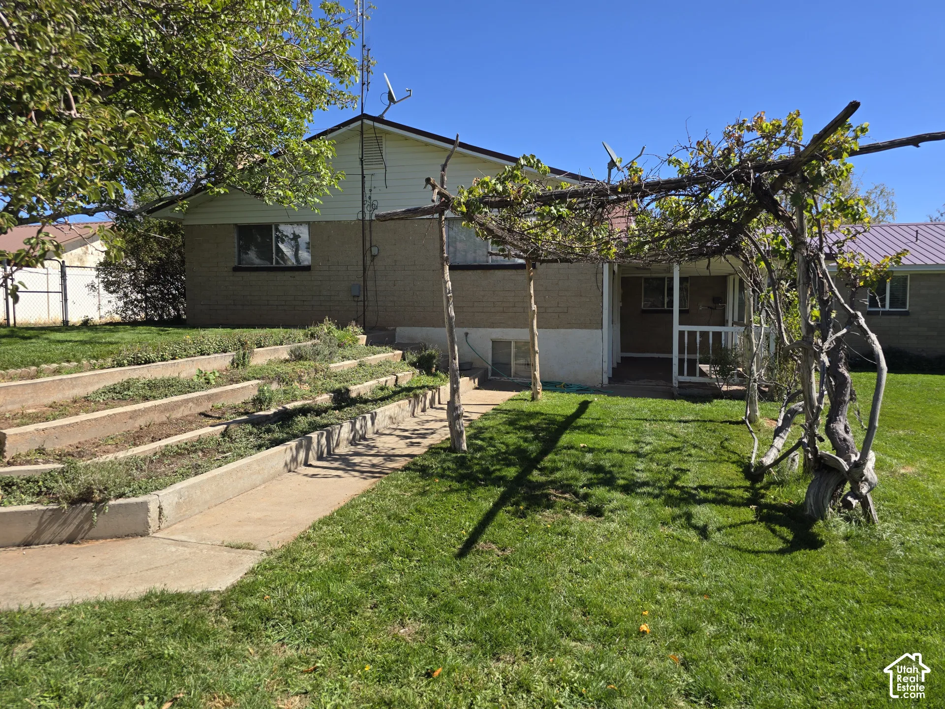 Rear exterior with a concrete patio, wood railing, and brick and siding facade