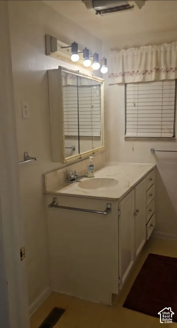 Integrated vanity with an oval sink and a light-toned countertop, complemented by a wall-mounted medicine cabinet with a mirror