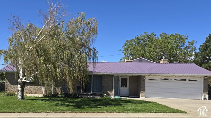 Purple metal roof, brick and stone exterior, attached two-car garage, mature landscaping, and a manicured front lawn