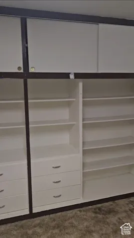 Built-in storage system featuring white cabinetry, multiple shelves, and integrated drawers with silver-finish pulls