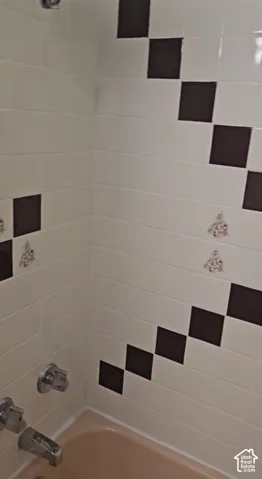 Wall-mounted shower head, chrome fixtures, brown and cream tile, tile with decorative accents, pink bathtub