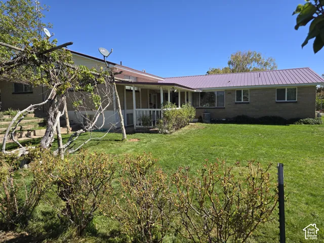 Expansive lawn with mature landscaping, a covered patio, and a metal roof