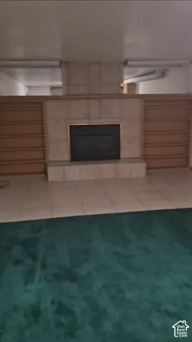 Fireplace with a tile surround and hearth, flanked by built-in shelving units