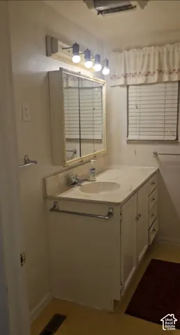Integrated vanity with an oval sink and a light-toned countertop, complemented by a wall-mounted medicine cabinet with a mirror