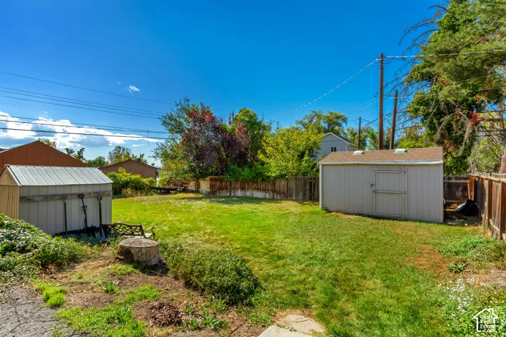 Expansive grassy backyard with two storage sheds and wood fencing