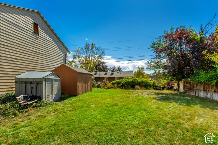 Expansive green lawn with two storage sheds and a partial wood fence
