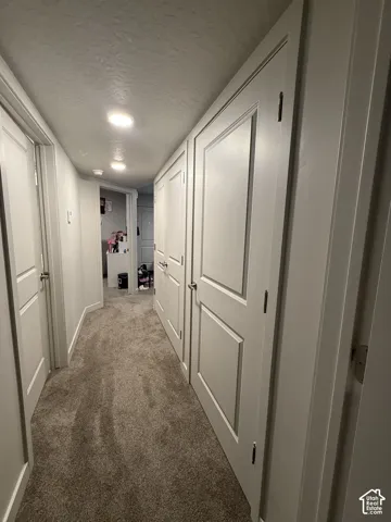 Hallway featuring recessed lighting, paneled doors, and plush carpeting