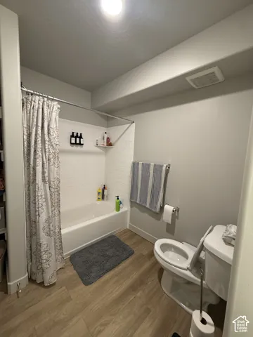 Bathtub with white subway tile surround, wood-finish flooring, and recessed ceiling lighting