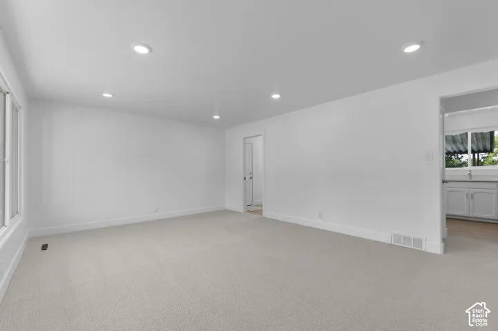 Recessed ceiling lighting with a light-toned carpet flooring and white painted walls