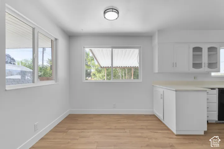 Wood-finish flooring, white walls, and built-in white cabinetry with glass-front uppers