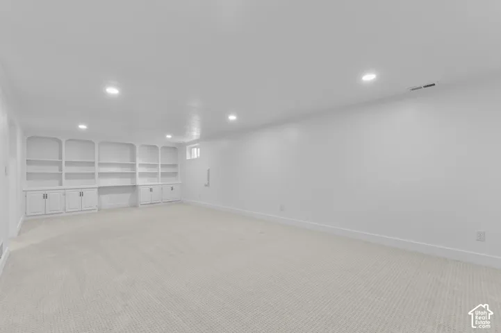 Expansive room featuring built-in cabinetry, recessed lighting, and light-toned carpeting