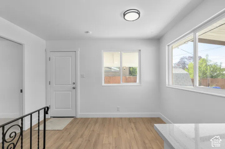 Wood-finish flooring, white paneled doors, multiple windows for natural illumination, flush-mount ceiling light fixture, and a partial quartz countertop