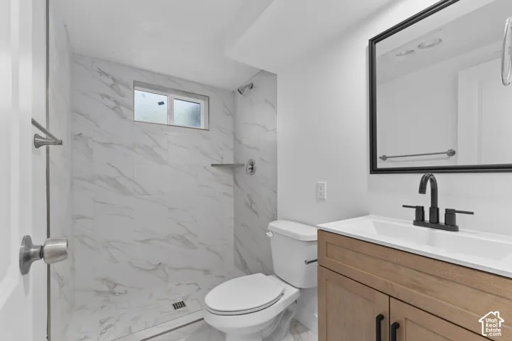 Bathroom featuring a wood-finish vanity with a single sink, matte black faucet, and a large mirror