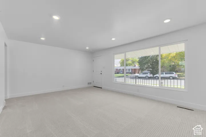Recessed lighting, light-toned carpeting, white walls, and a large multi-pane window