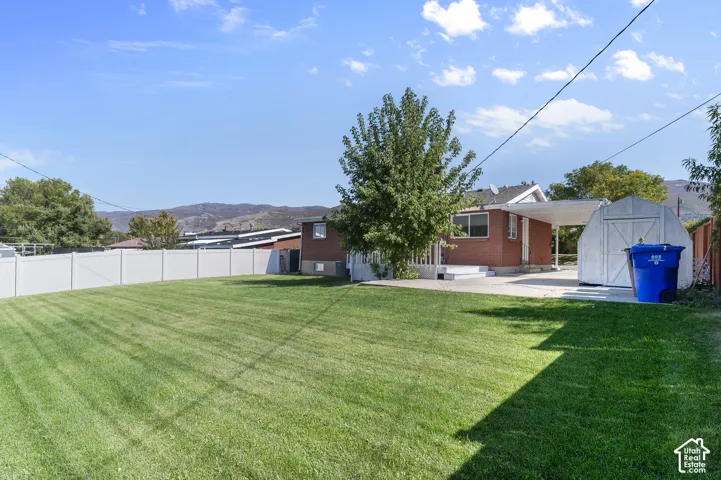 Expansive lawn with a white privacy fence and a brick-finish exterior