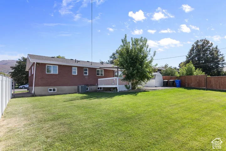 Expansive rear yard featuring green lawn, a white PVC fence, and a wooden privacy fence