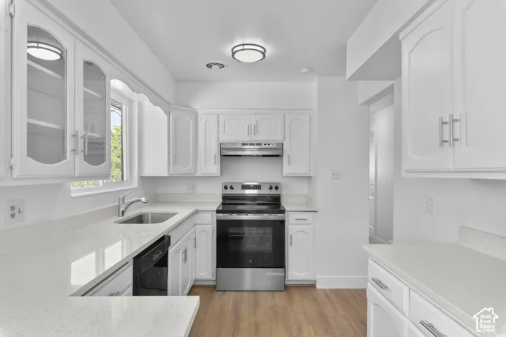 White cabinetry with brushed nickel hardware, stainless steel appliances, light-toned countertops, wood-finish flooring, and a stainless steel sink with a gooseneck faucet