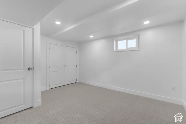 Recessed lighting illuminates the space, featuring a window, double-door closet, and carpeted flooring