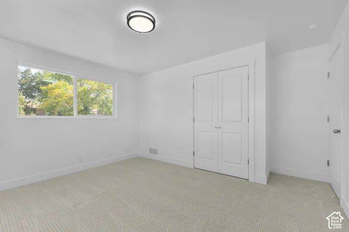 Neutral-toned carpeting, white walls, and a modern flush-mount ceiling light