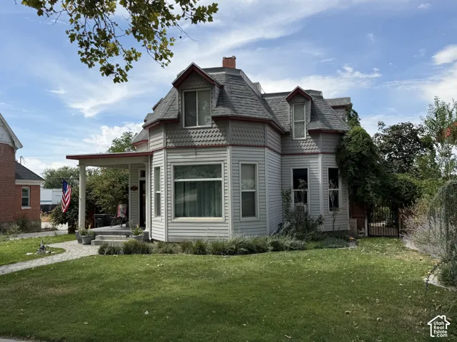 Victorian-style residence featuring a prominent bay window, a covered porch, and a dormered roofline with decorative shingles