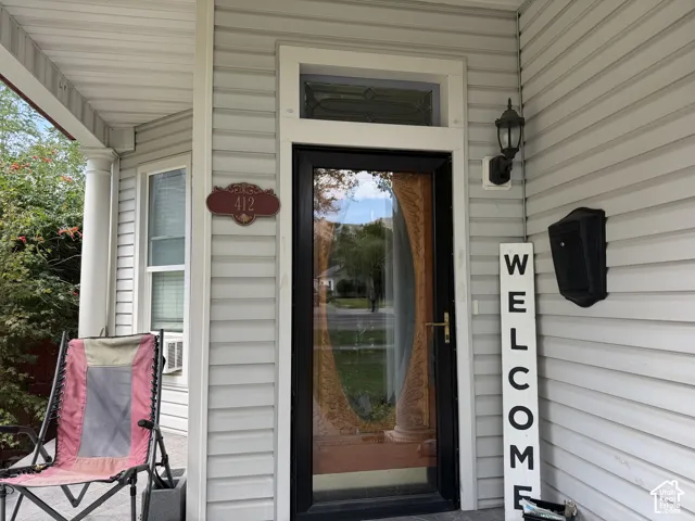 Entryway featuring a black full-view storm door, decorative transom window, wall-mounted exterior light fixture, and a black mailbox