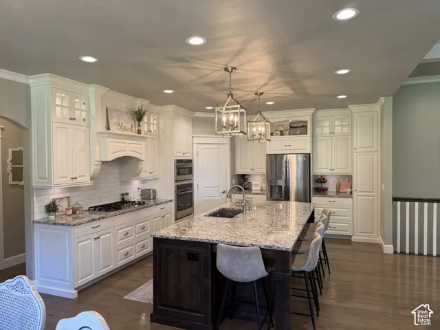 Gourmet kitchen featuring a large central island, white shaker cabinetry, stainless steel appliances, and granite countertops