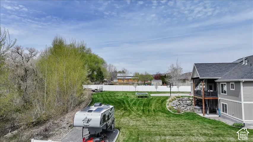 Expansive lawn with a retaining wall, a multi-level deck, and a gravel parking area