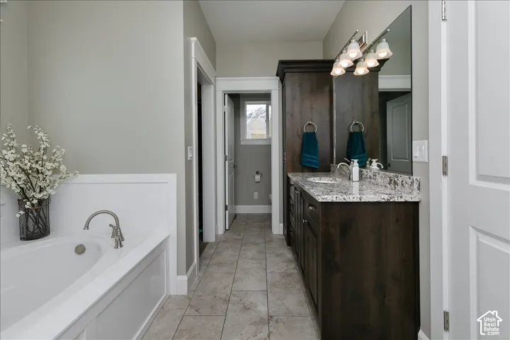 Dual vanity with stone countertop, dark wood-finish cabinetry, and tiled flooring