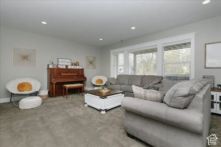 Recessed lighting illuminates the living area with soft gray wall finishes and carpeting