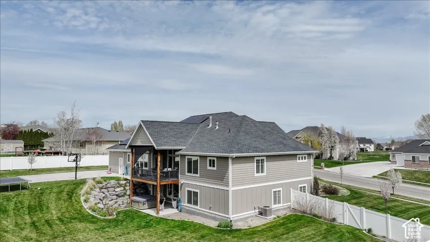 Two-story exterior with horizontal siding, covered deck, lower patio, and solar panels