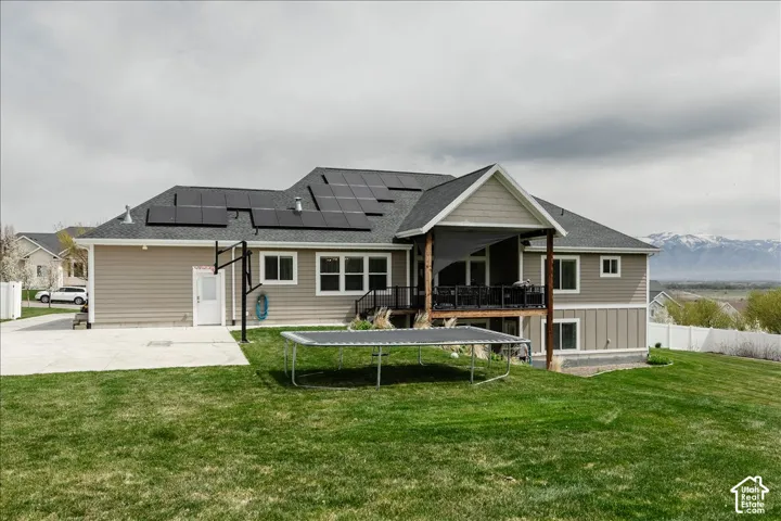 Expansive rear elevation featuring a covered deck, multiple windows, and a concrete patio