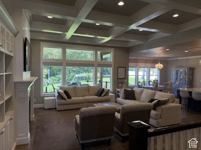 Coffered ceiling with recessed lighting, built-in shelving, fireplace with mantle, and large picture windows