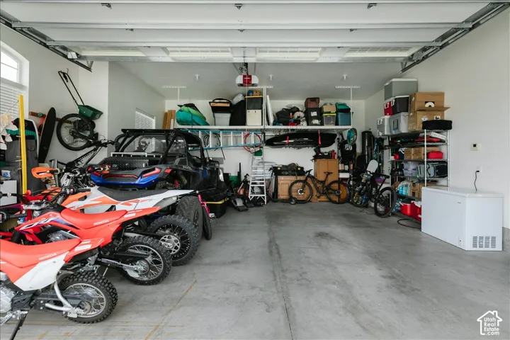 Spacious attached garage with concrete flooring, overhead lighting, and built-in shelving