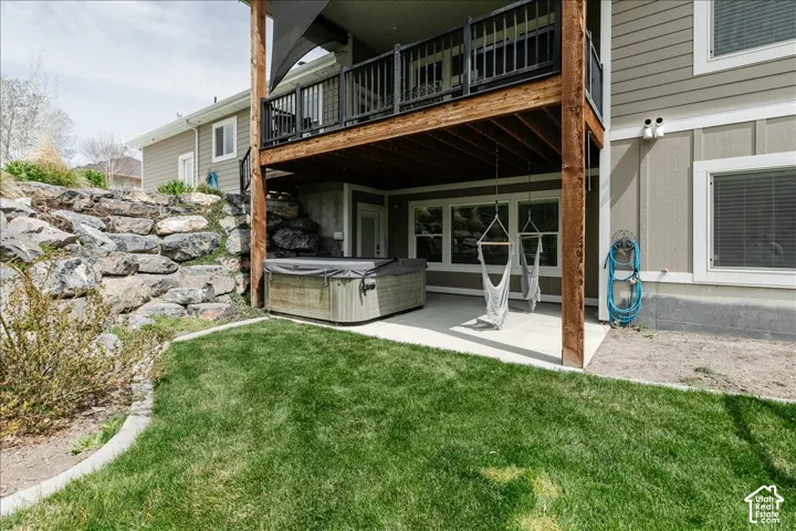 Expansive backyard with a manicured lawn, concrete patio, and stone retaining wall