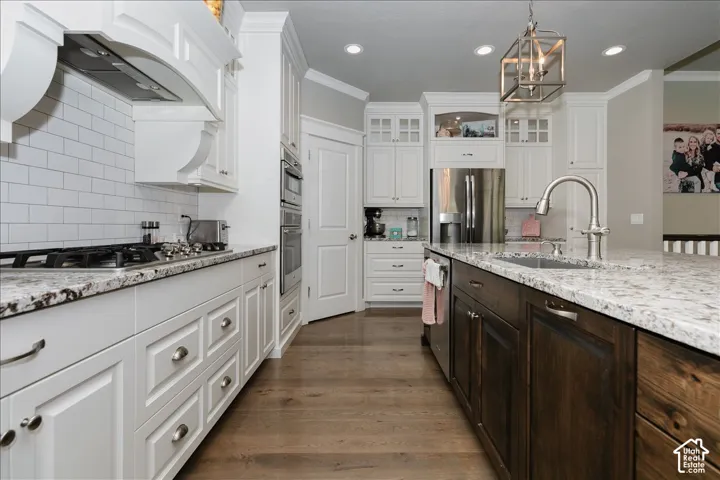 Gourmet kitchen with white shaker cabinetry, stainless steel appliances, granite countertops, and wood-finish flooring