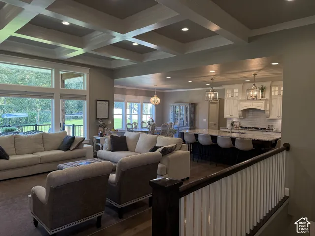 Coffered ceiling with recessed lighting, large windows, wood-finish flooring, kitchen island with seating, and white cabinetry