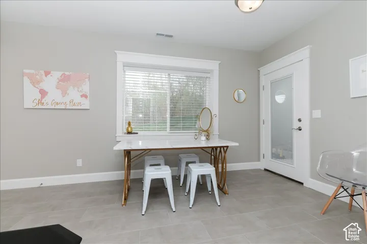 Recessed lighting, large window with blinds, white trim, light gray wall paint, and gray tile flooring