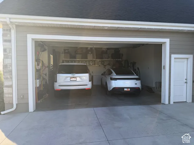 Two-car garage with concrete flooring, shelving, and interior access door