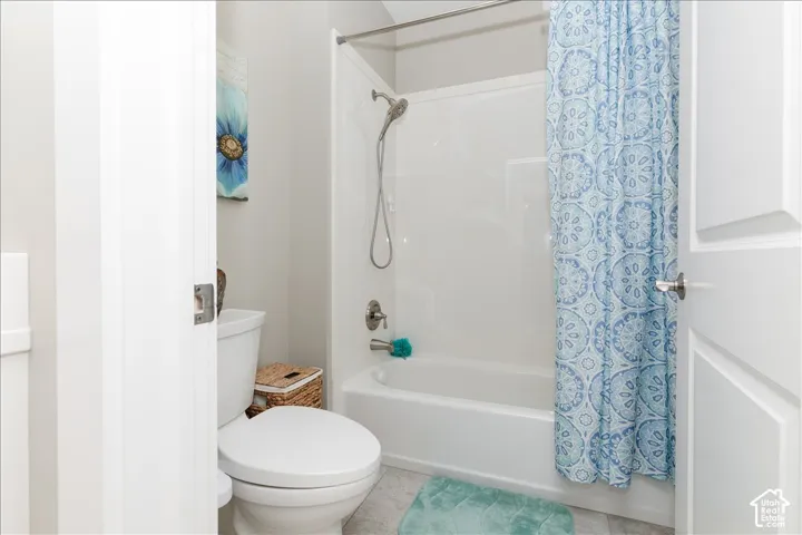 White paneled interior doors, a toilet with a round bowl, a built-in shower/tub combination, and a brushed nickel shower head