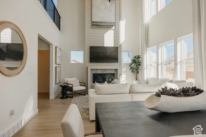 Soaring ceilings with extensive window detailing, a contemporary fireplace with shiplap accent wall, wood-finish flooring, and a second-story interior balcony