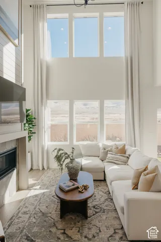 Two-story living area with high ceilings, featuring a built-in fireplace with a tile surround, and light wood-finish flooring