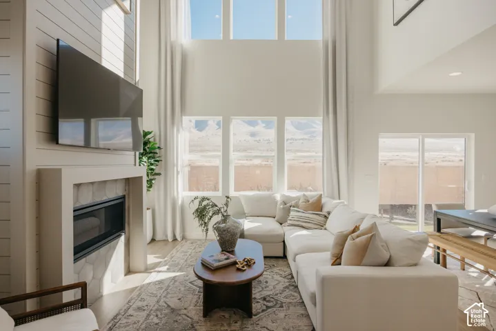 Living area featuring a fireplace with a tiled surround, wood-finish flooring, high ceilings, and multiple windows